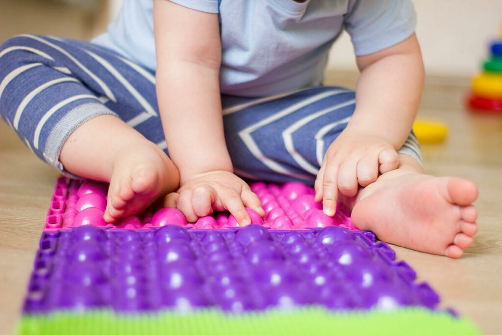 toddler-boy-sitting-on-orthopedic-massage-mat